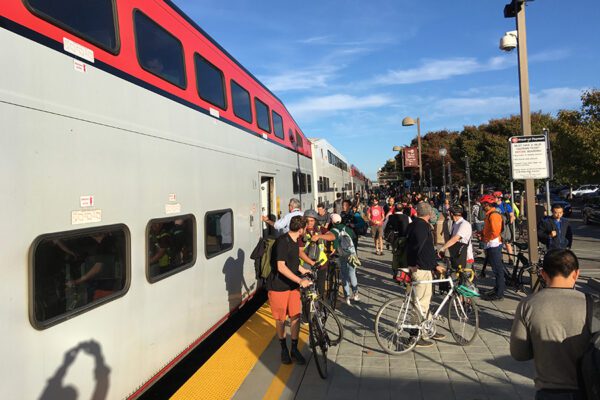 People getting on and off a reginoal train in Mountainview. Several have bicycles.