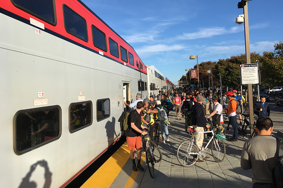 People getting on and off a reginoal train in Mountainview.  Several have bicycles.