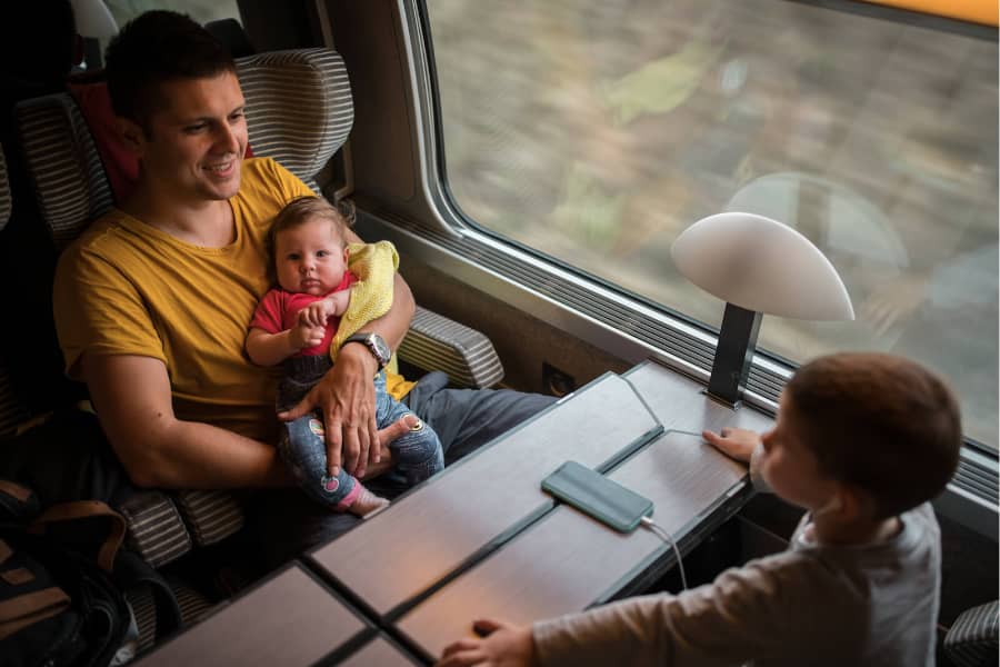 Father holding baby, son facing them from other side of table on TGV train.