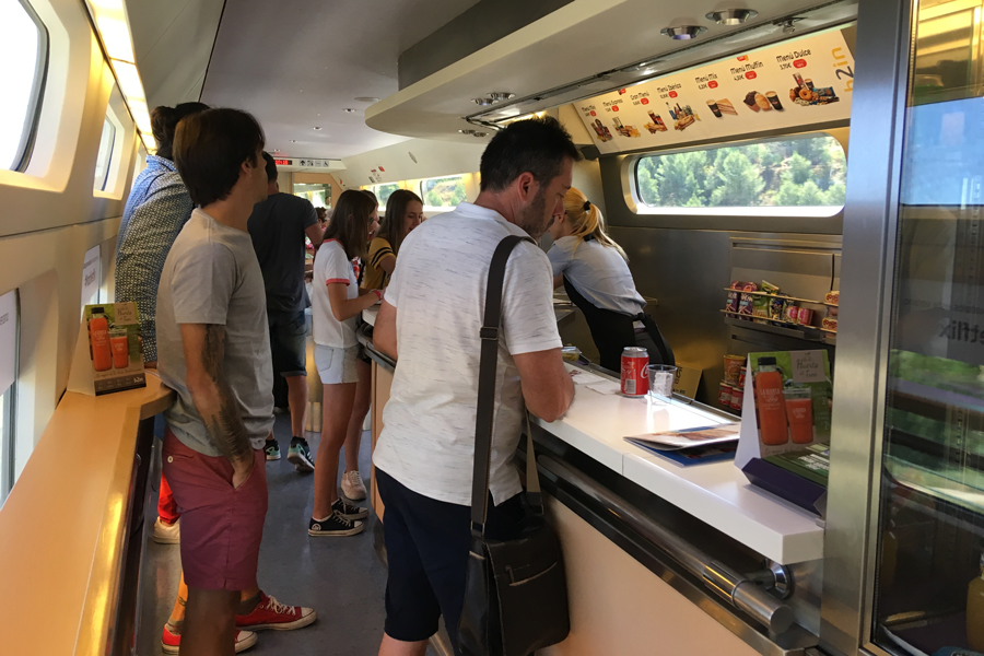 AVE_Cafe_IMG_6376_Harnish_900x600 People are gathered at the counter in a cafe car on a high-speed train.