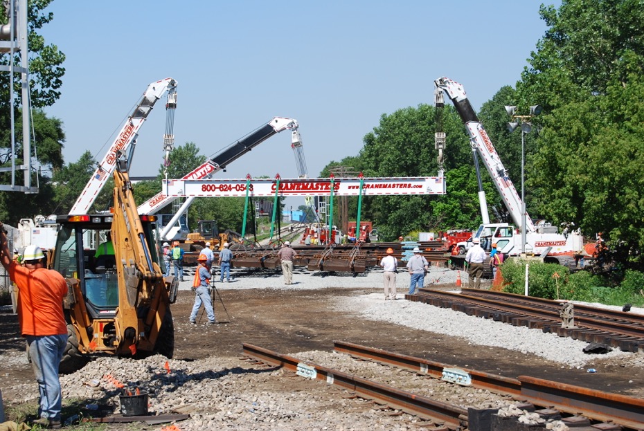 Two walking cranes are placing a railroad diamond in place.