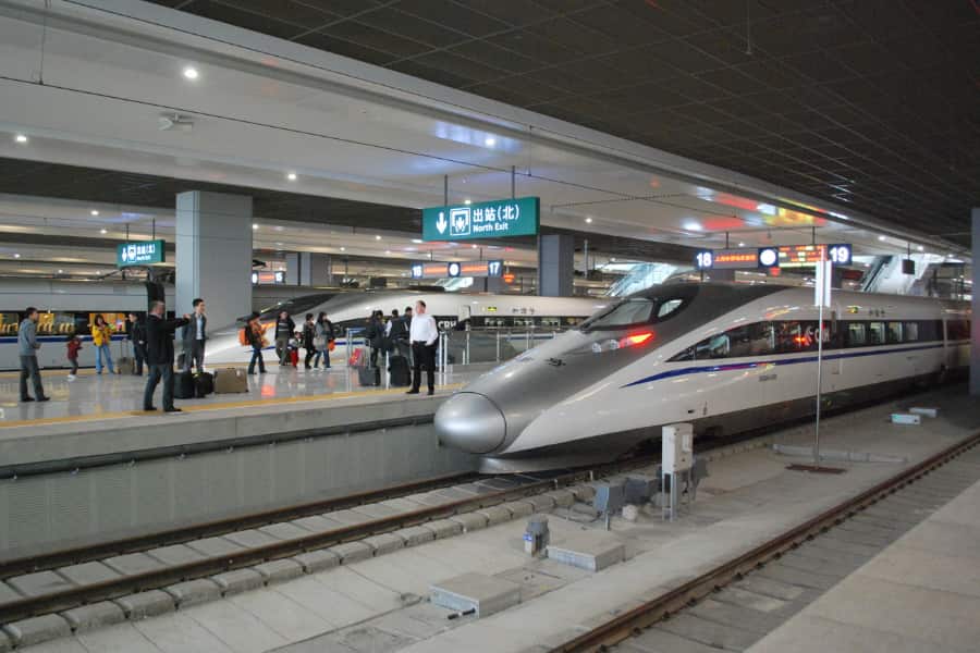 An American businessman is posing in front of a high-speed train at Shanghai Hongqiao railway station.
