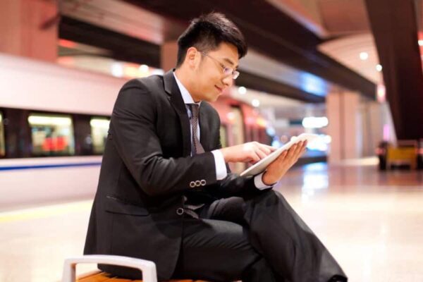 man using tablet on train platform
