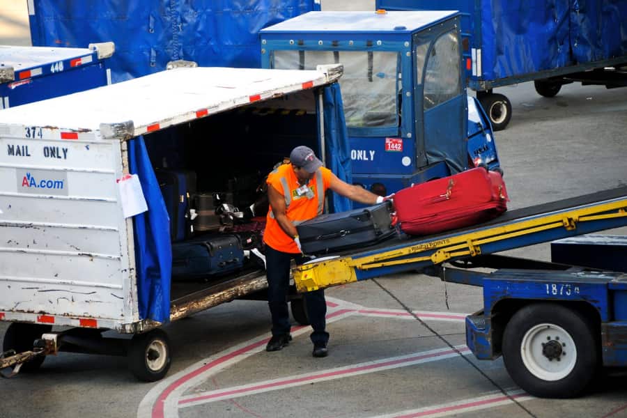 A ground crew worker is unloading baggage from a plane at O'Hare.