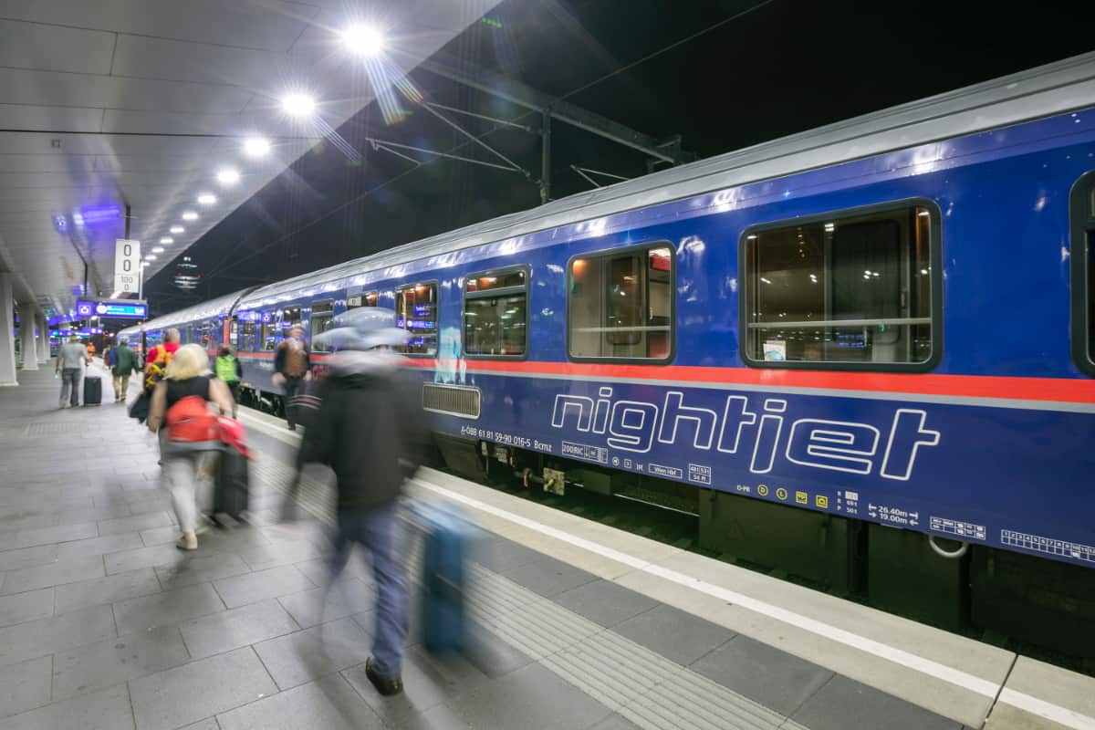 Nightjet train at station with moving passengers on platform