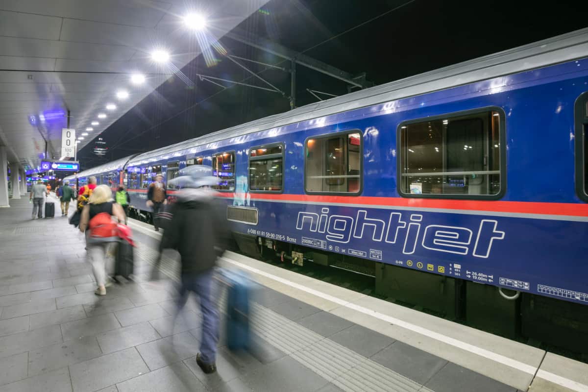 1200x800 Nightjet train at station with moving passengers on platform