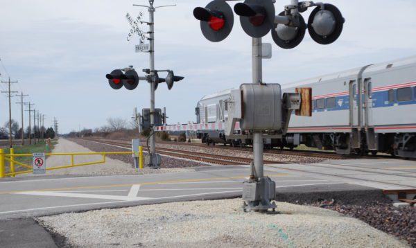 An Amtrak train is passing through a grade crossing in the Illinois countryside.