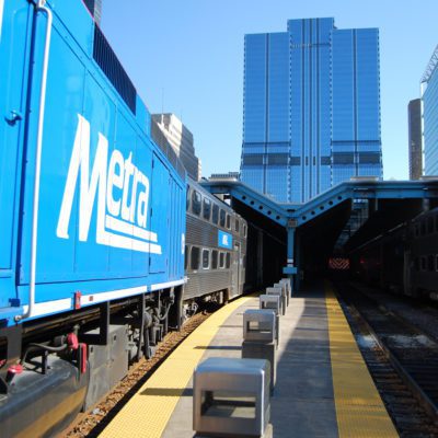 Metra train leaving Ogilvie Station viewed from end of platform, 500 W Madison in background.