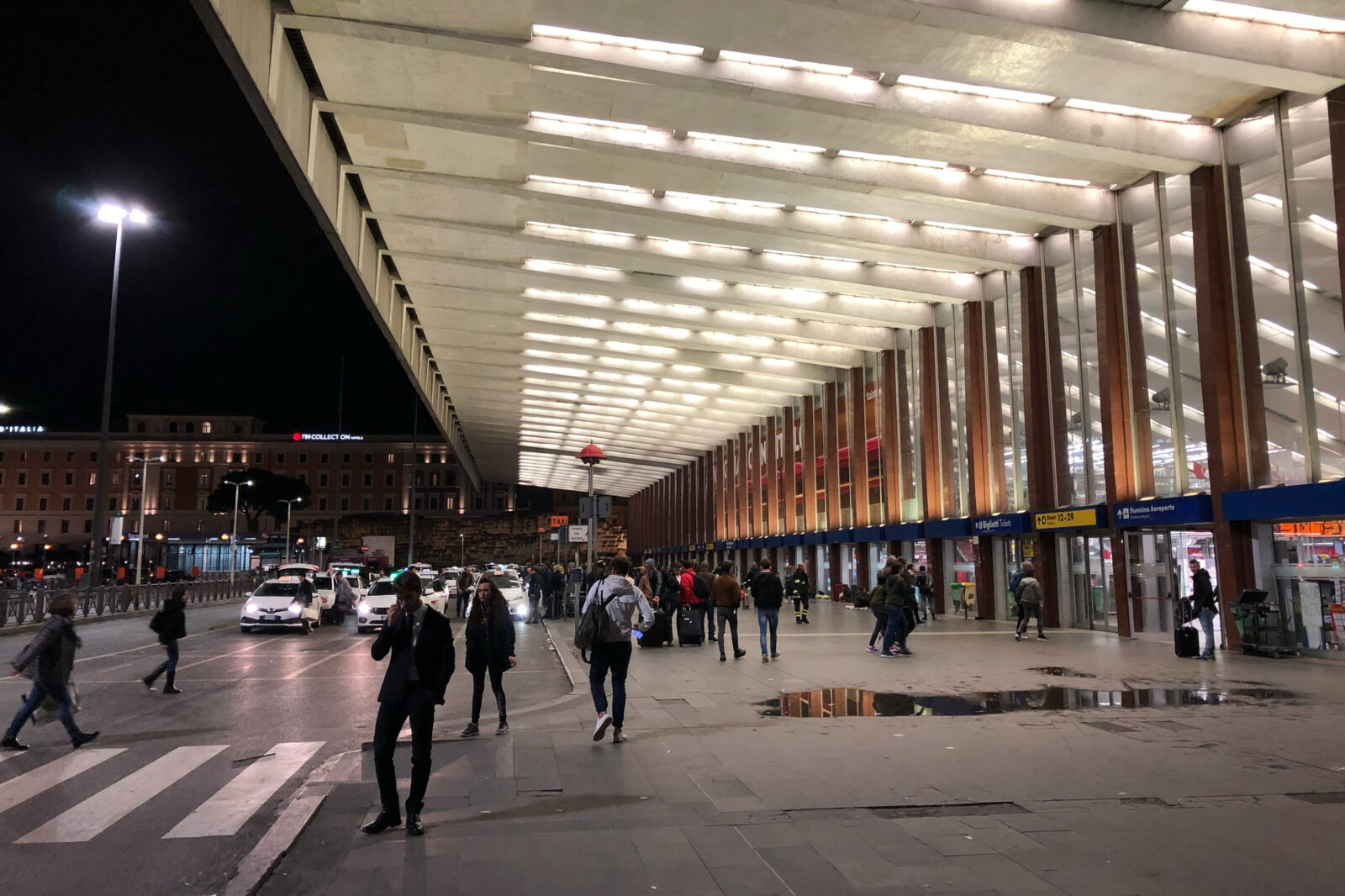 The front area of Rome Termini station is busy with travelers and waiting taxis.