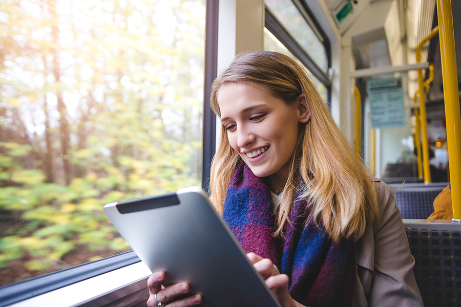 A woman is reading her IAD while riding on the train.