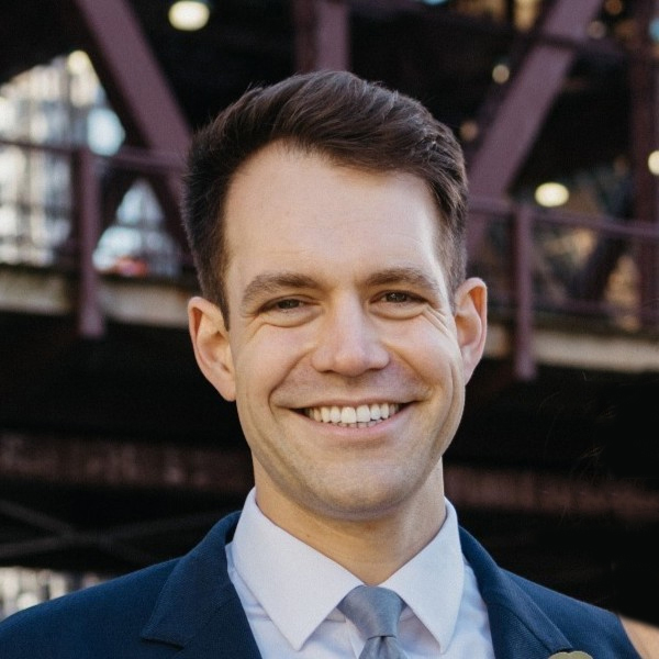 Portrait of Nick Carney, with Chicago EL bridge in background.