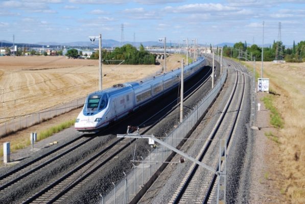 An AVE train is passing under a bridge near Ciudad Real Spain.