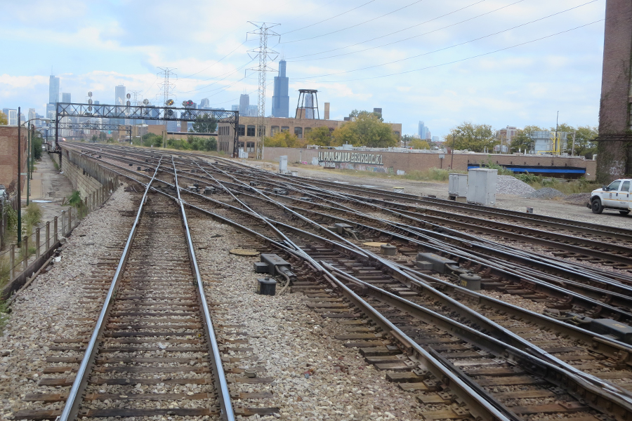 A view from the rear window of a train with A-2 Crossing in the foreground and the Chicago skyline in the background.