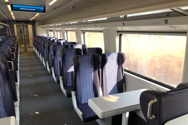 Interior of a coach car in Amtrak Midwest service. There is a table with four seats facing it. Most seats are theatre style.