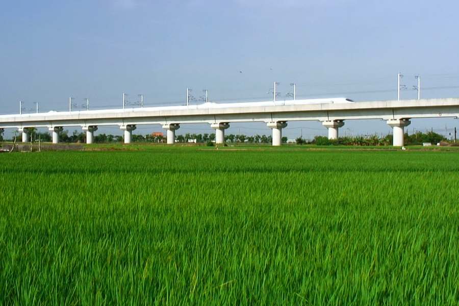 A Shinkesen train on a viaduct over a field
