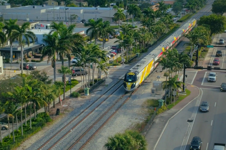 A Brightline train is crossing a highway in southern Florida.