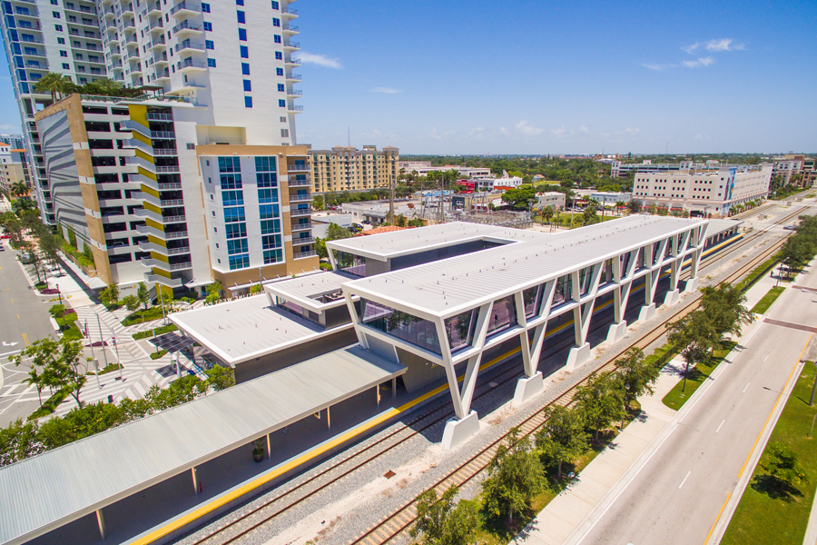 Brightline's West Palm Beach station is shown from above.  A new high-rise is next door.