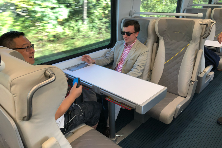 Two passengers are sitting at a table on a Brightline train.