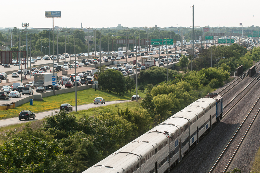 An outbound Metra train is passing traffic on the Kennedy Expressway.