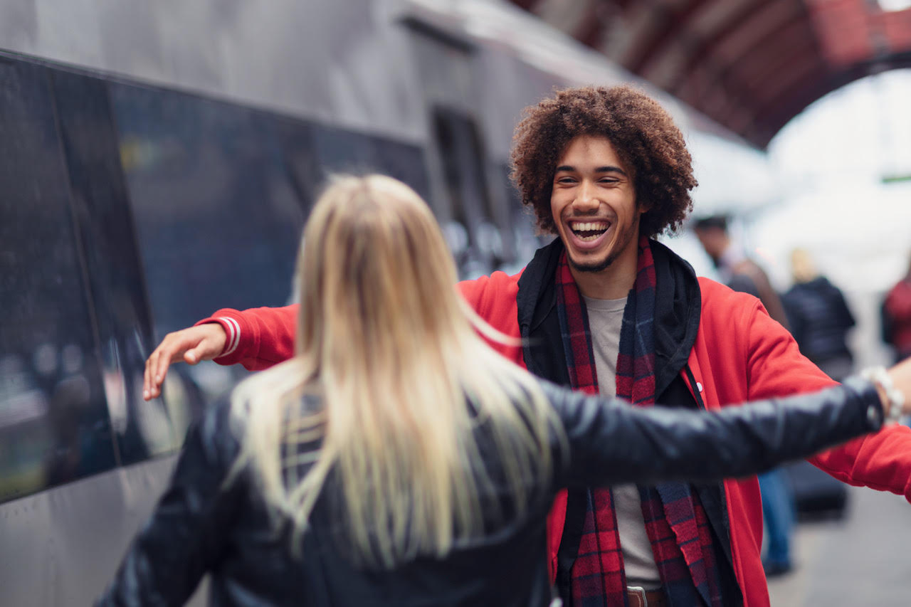 Two people about to hug on a train platform