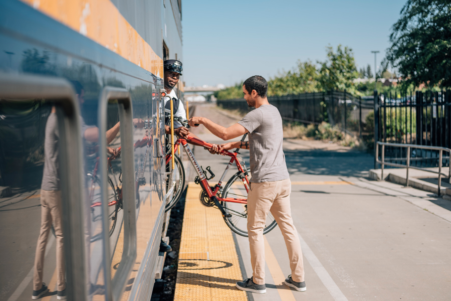 The train conductor is helping a man load his bike onto a San Joaquin train in the Central Valley.