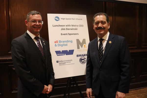 Speakers smile next to HSRA sign showing event sponsors