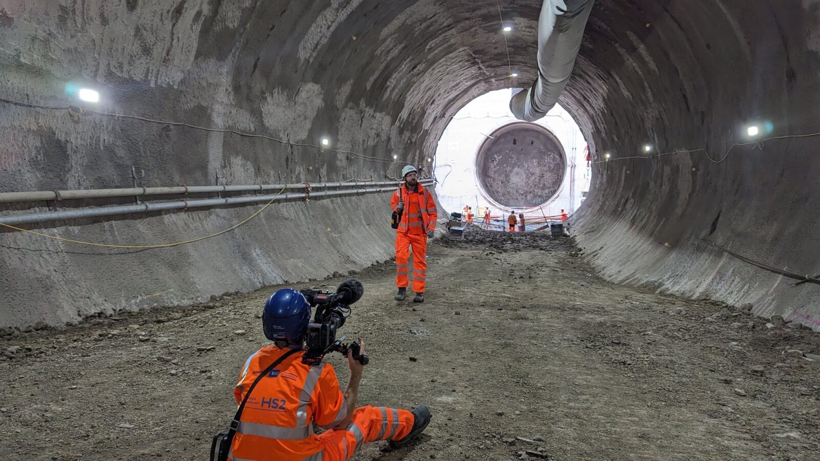 Two construction workers a working in a railroad tunnel.