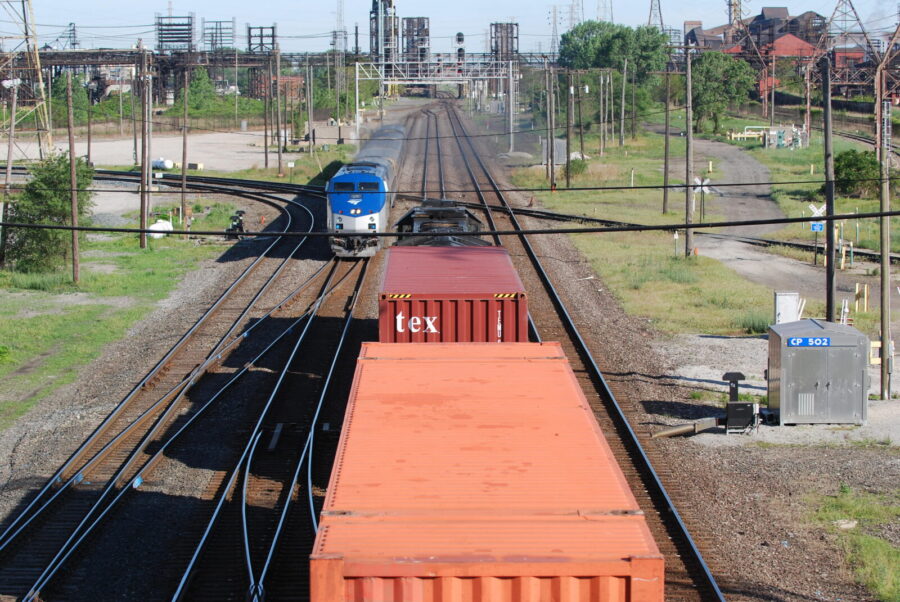An Amtrak train is passing a Norfolk Southern stack train.