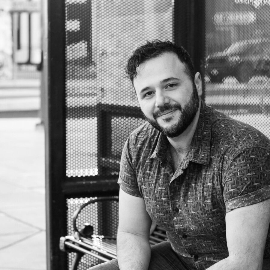 A black and white image of a man sitting at a bus stop