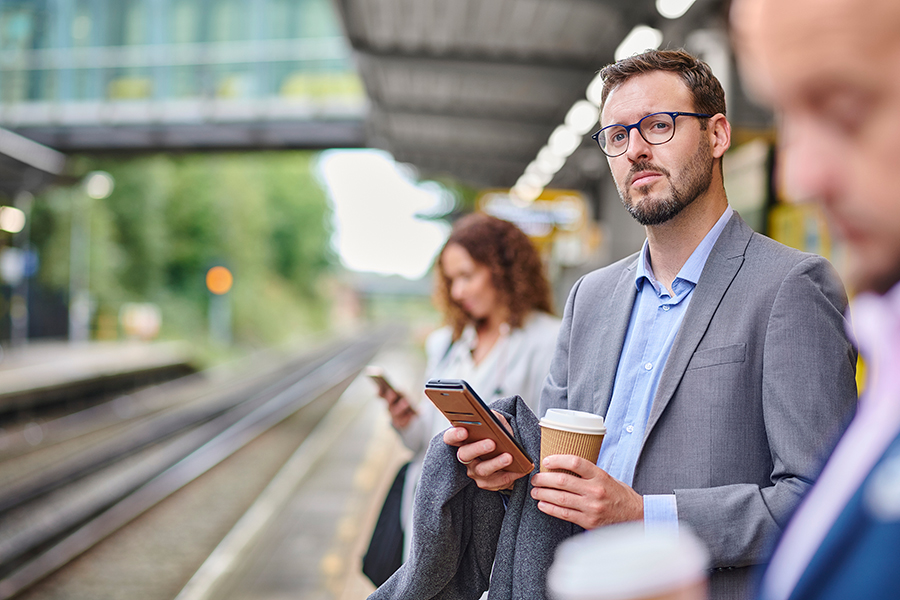 A dude is standing on a train platform looking to see if the train is coming.